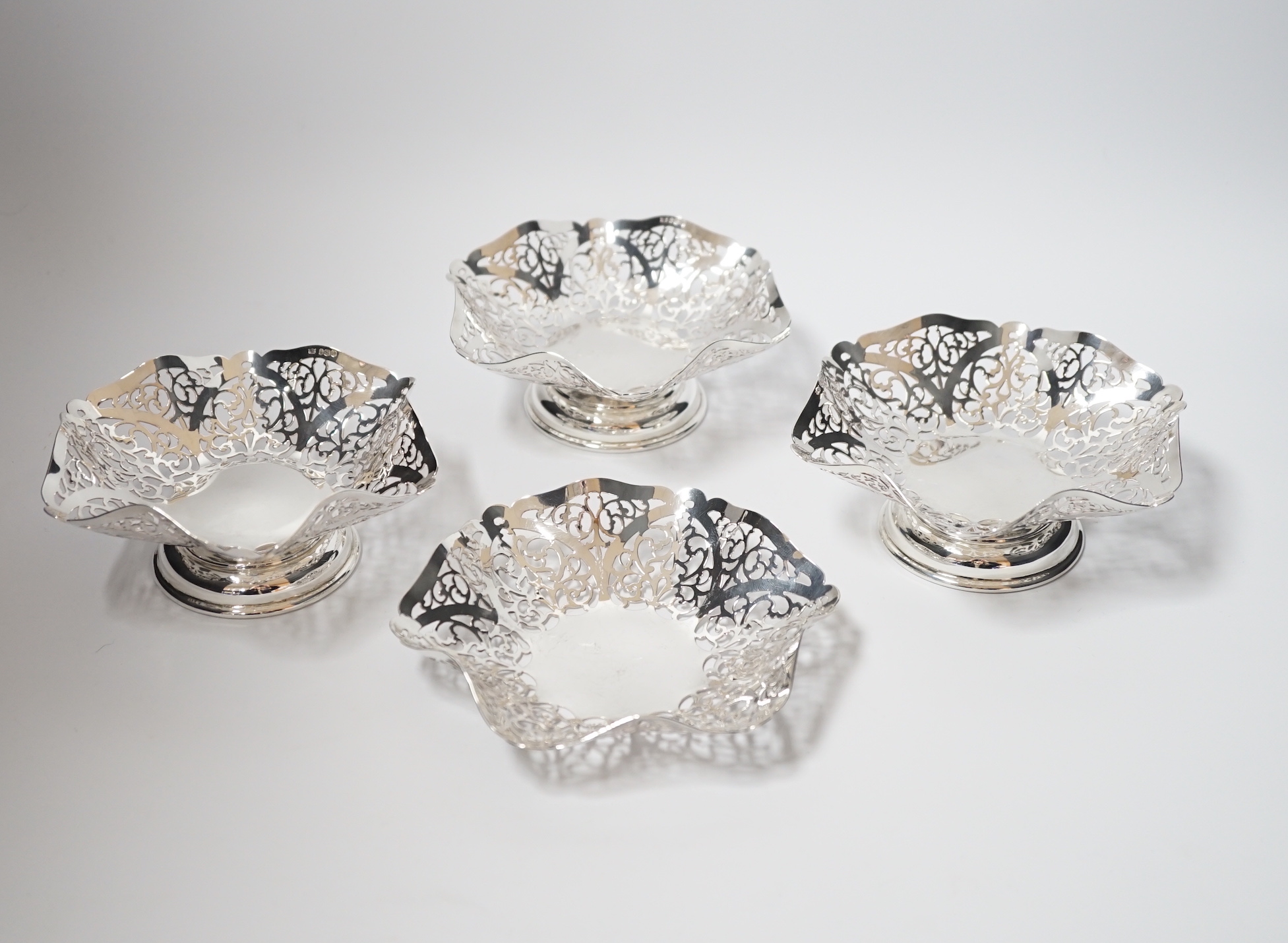 A set of three Elizabeth II pierced silver bonbon dishes, William Bush & Son, Sheffield, 1962, 14.2cm and one other similar silver shallow dish, 16oz.